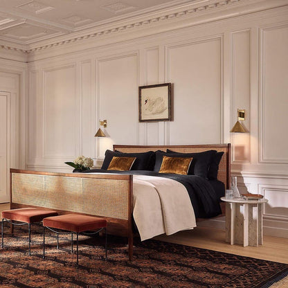 Luxurious bedroom with a wooden bed, black and gold bedding, and decorative handmade rug.