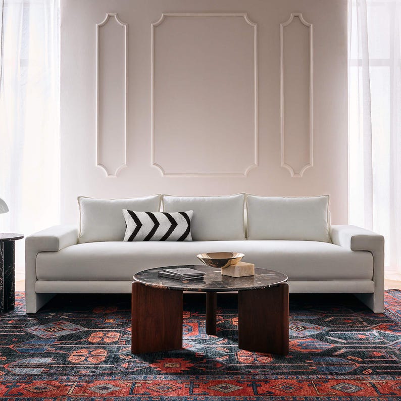 Modern living room with a white sofa, decorative pillows, and a patterned hand knotted oushak rug from Bisha Rugs.