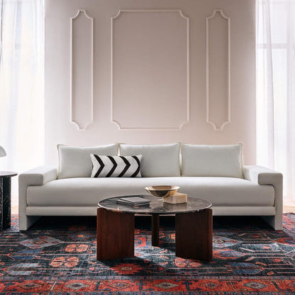 Modern living room with a white sofa, decorative pillows, and a patterned hand knotted oushak rug from Bisha Rugs.