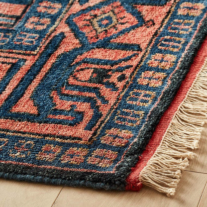 Close-up of a patterned oushak rug with blue and red colors on a wooden floor.