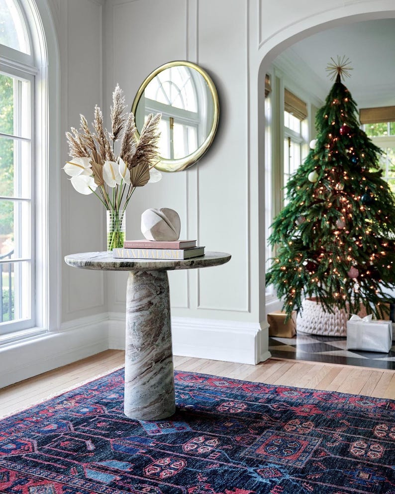 Decorative interior with a marble table, Christmas tree, hand knotted oushak rug, and decorative mirror.